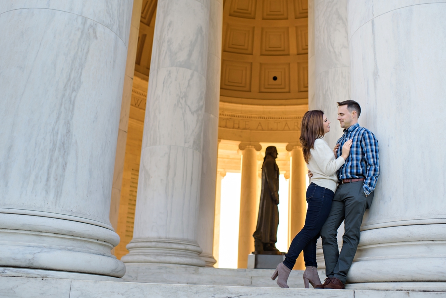 An adorable couple leaning against the columns of the lincoln memorial.